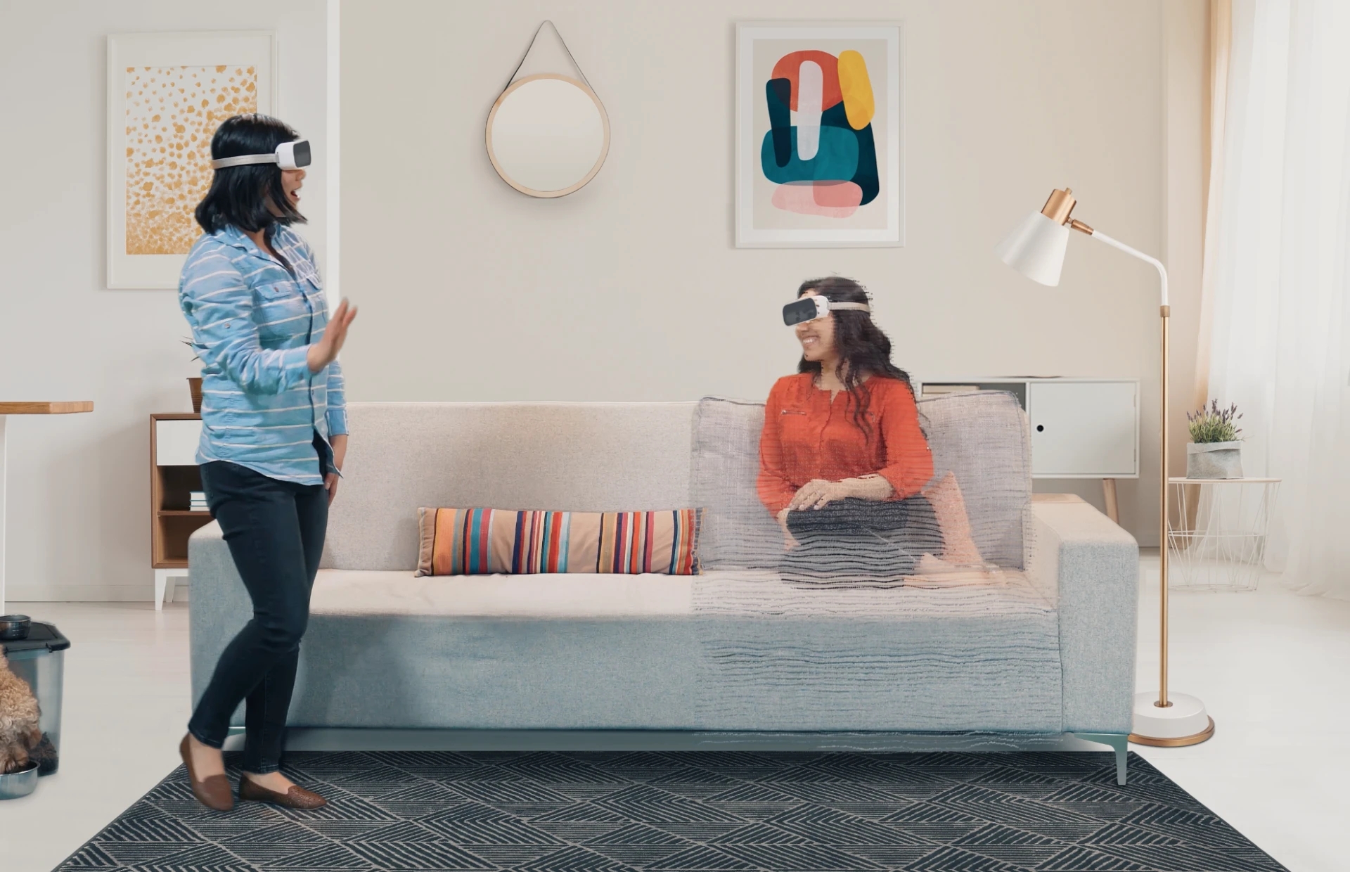composite still from a video showing users with vr headsets that show the user's eyes through the front visor chatting together in a living room, one user appears to be virtually there